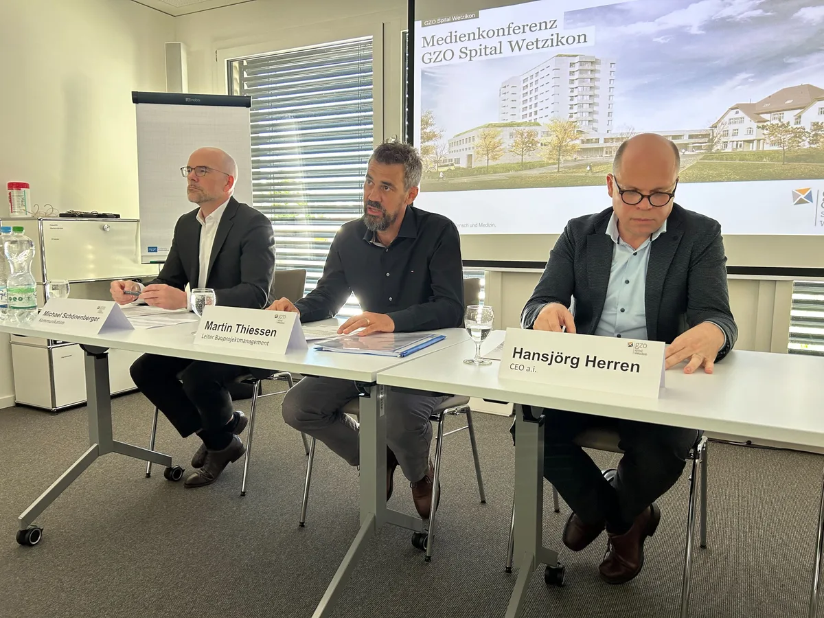 Drei Personen sitzen an einem Tisch.